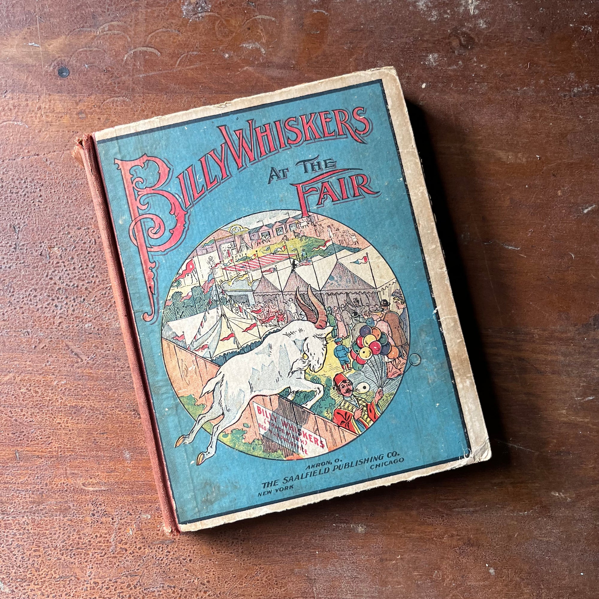 vintage children's chapter book, antique children's book, antiquarian book - Bill Whiskers Goes to the Fair written by F. G. Wheeler with illustrations by Arthur De Bebian - view of the front cover with an illustration of Billy Whiskers jumping over a fence at the fair