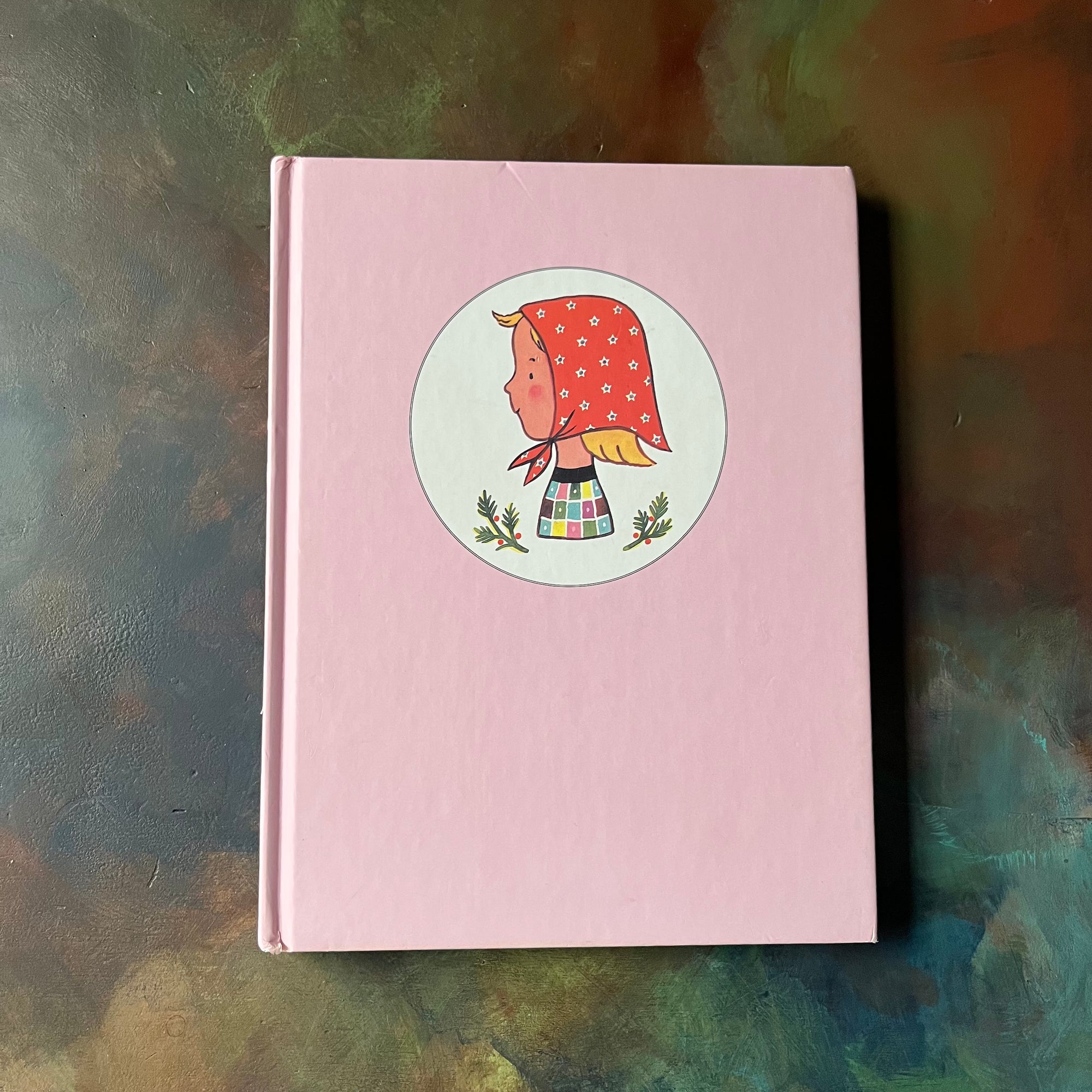 The Adventures of Jeanne-Marie by Francoise Seignobosc-1999 Edition-children's picture book-view of the front cover in pink with an illustration of Jeann-Marie in a circle wearing a handkerchief on her head