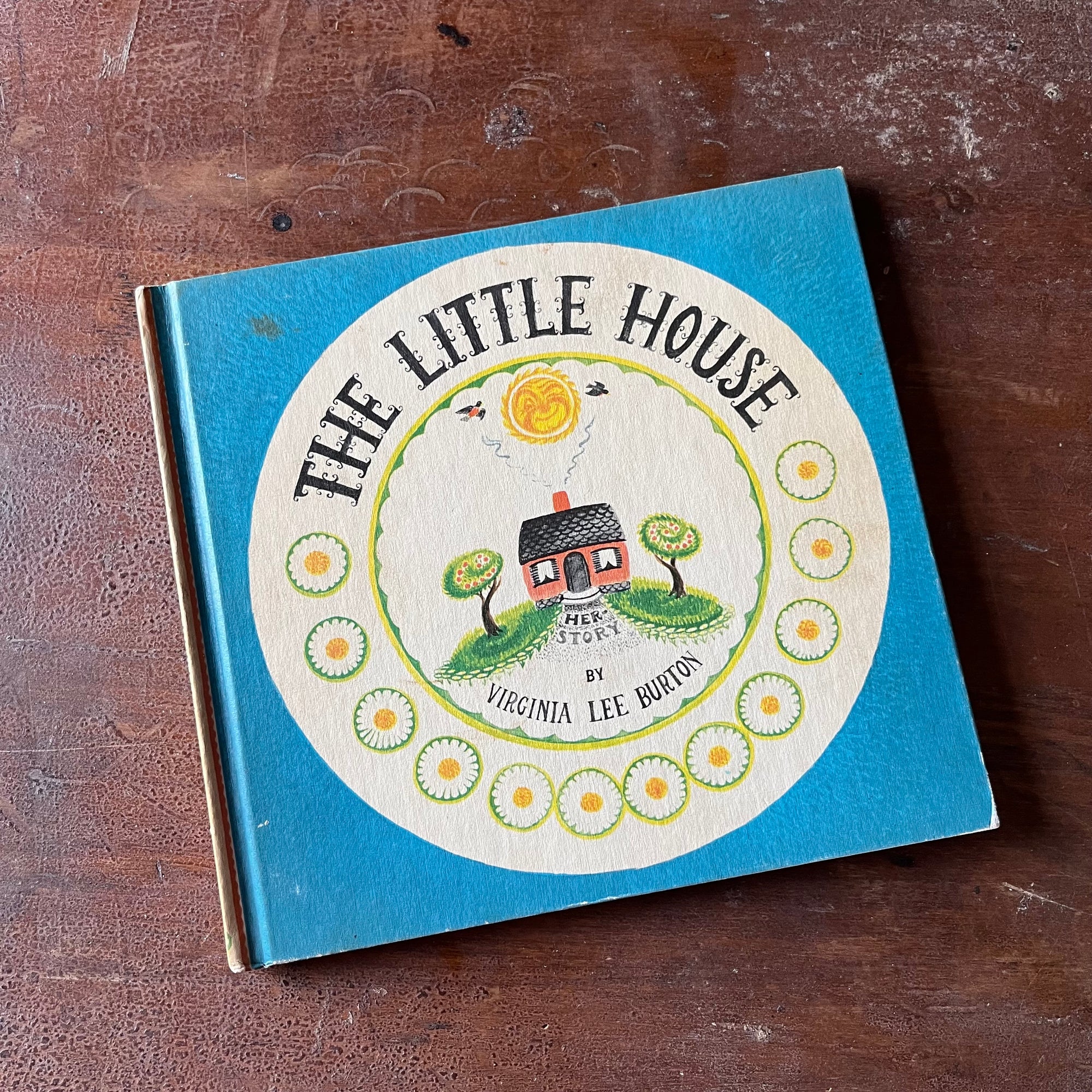 vintage children's picture book, Caldecott Award Winning Book - The Little House Written & Illustrated by Virginia Lee Burton - view of the front cover with an illustration of the little house beneath a smiling sun