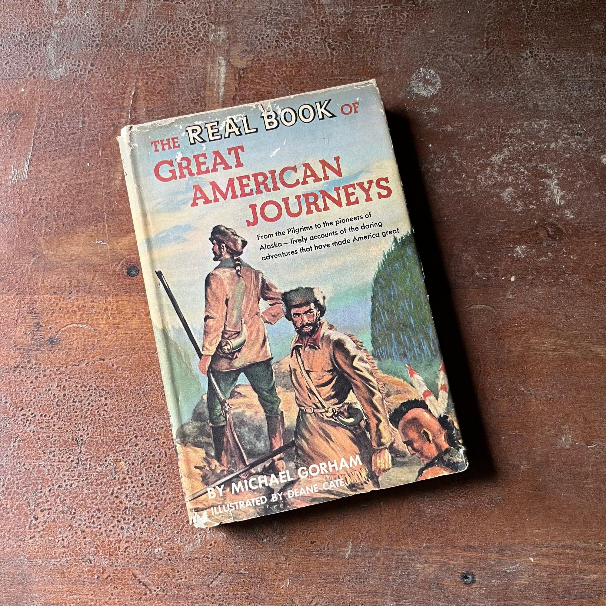 vintage children's book, vintage children's history book, vintage chapter book , The Real Book Series - The Real Book of Great American Journeys written by Michael Gorham & illustrated by Deane Cate - view of the dust jacket's front cover with an illustration of Lewis & Clark along with a native American male