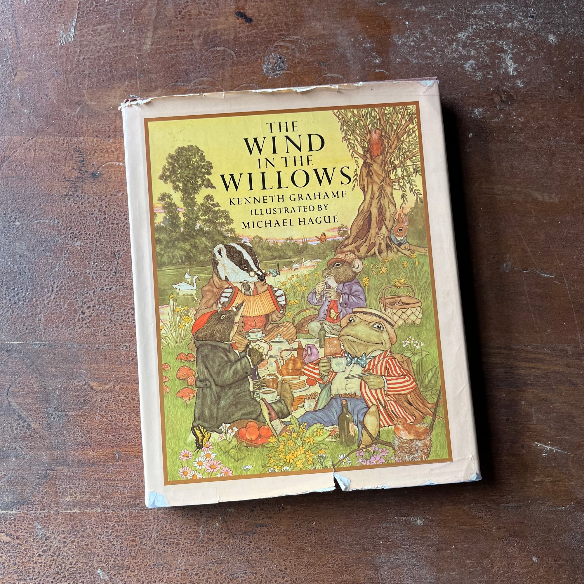 vintage children's chapter book, classic literature - The Wind in The Willows written by Kenneth Grahame with illustrations by Michel Hague - view of the dust jacket's front cover - note the wear around the edges