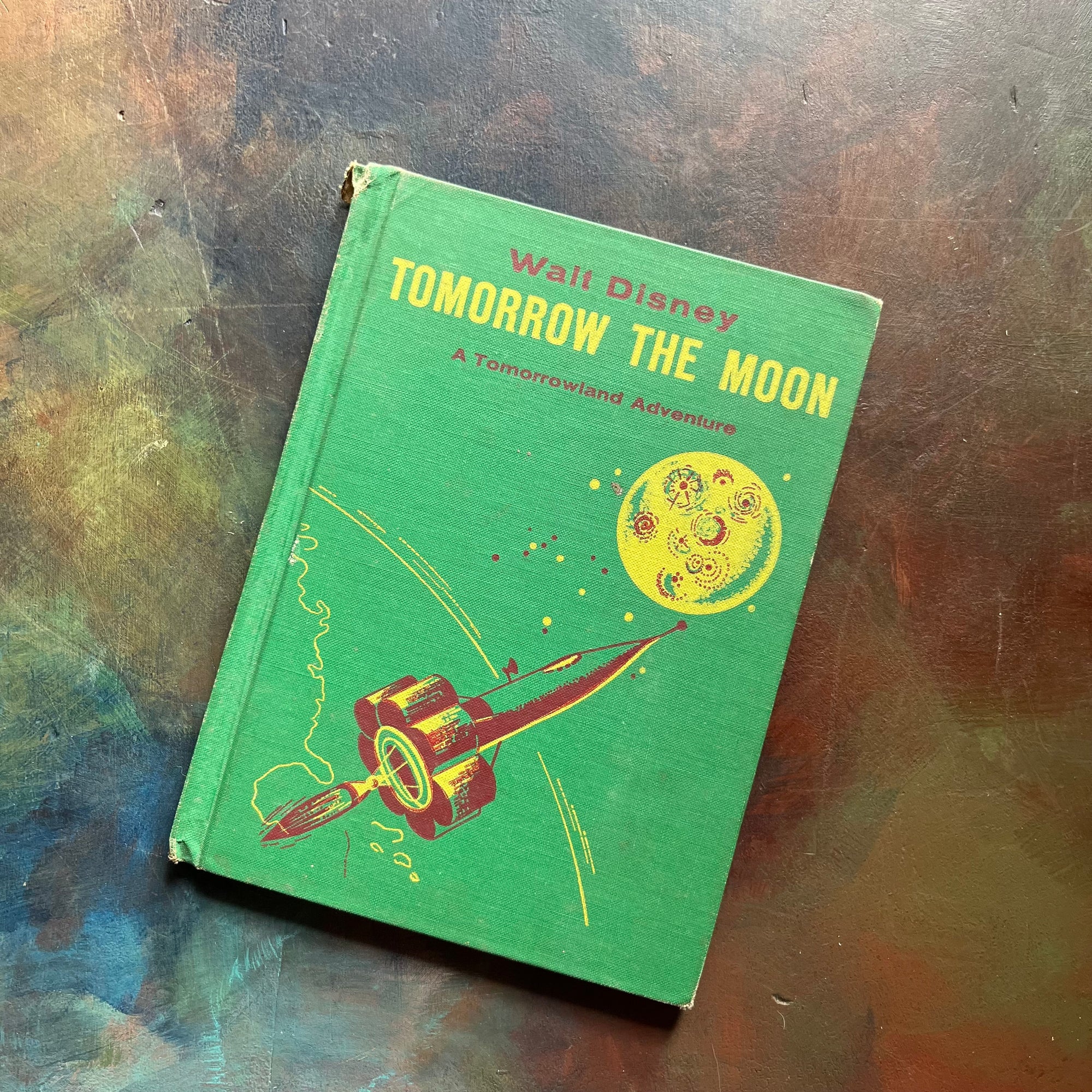 Vintage Green book titled 'Tomorrow the Moon' by Walt Disney on a textured surface-A Tomorrowland Adventure Book-Walt Disney Productions-living science book for kids-view of the front cover