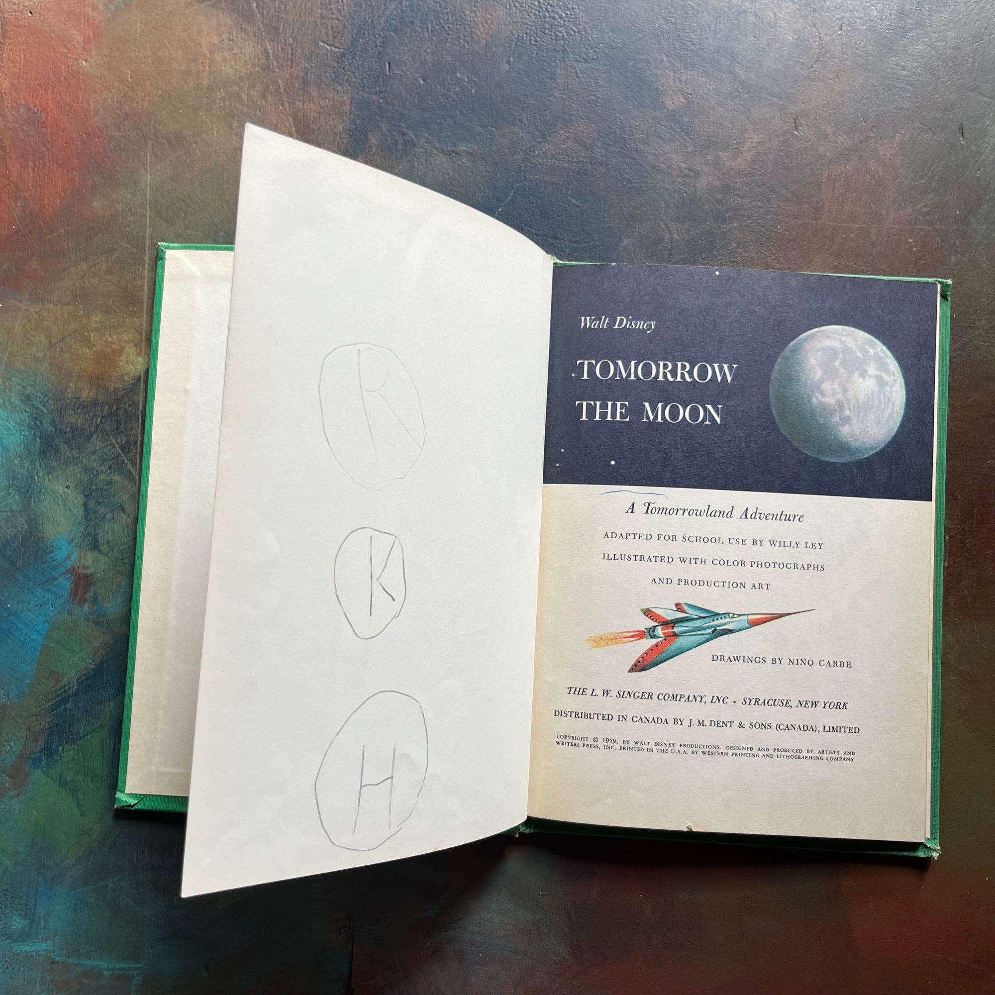Vintage Green book titled 'Tomorrow the Moon' by Walt Disney on a textured surface-A Tomorrowland Adventure Book-Walt Disney Productions-living science book for kids-view of the title page - note the pencil drawings on the page opposite the title page