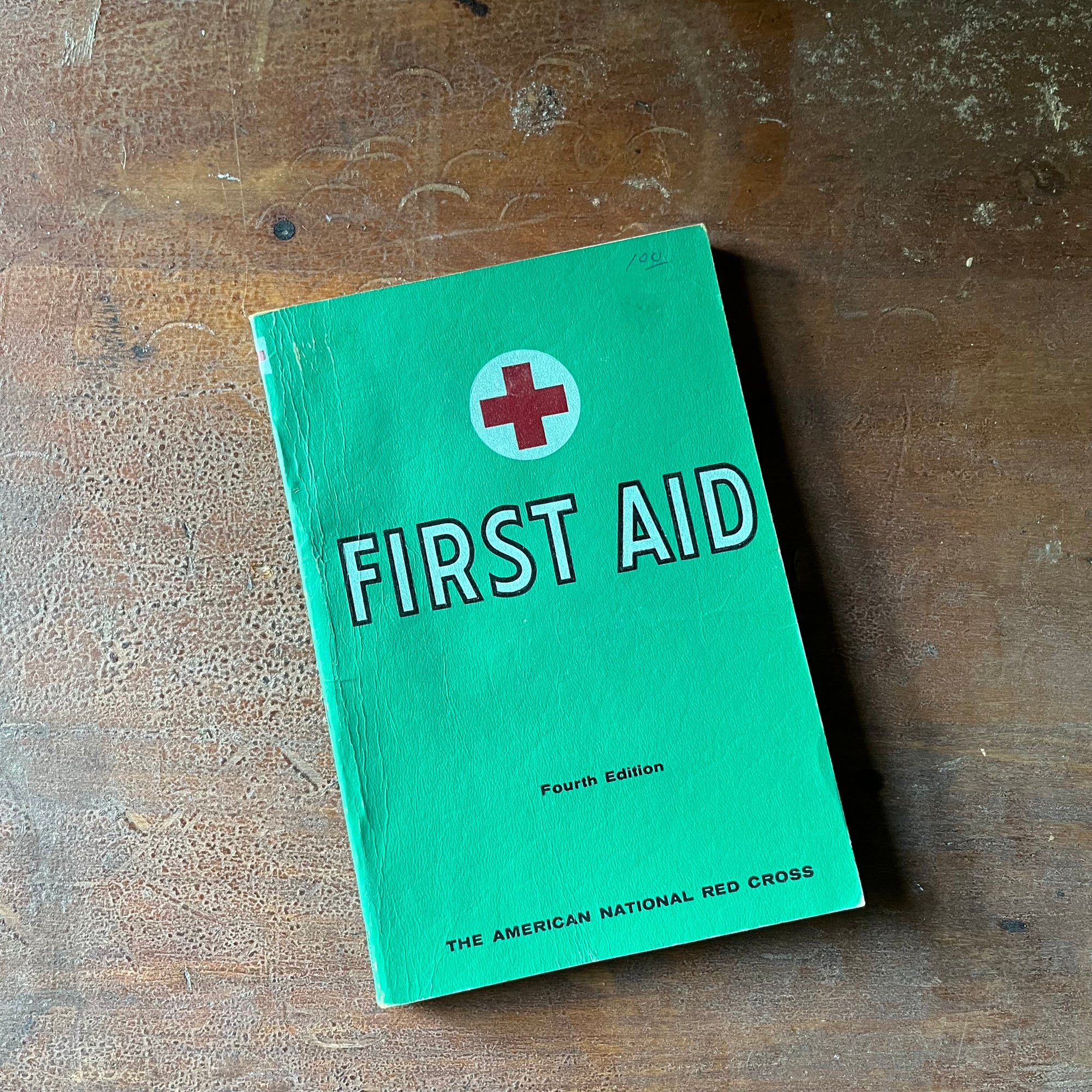 The American Red Cross First Aid Textbook 4th Edition - front cover shown sitting on a wood table