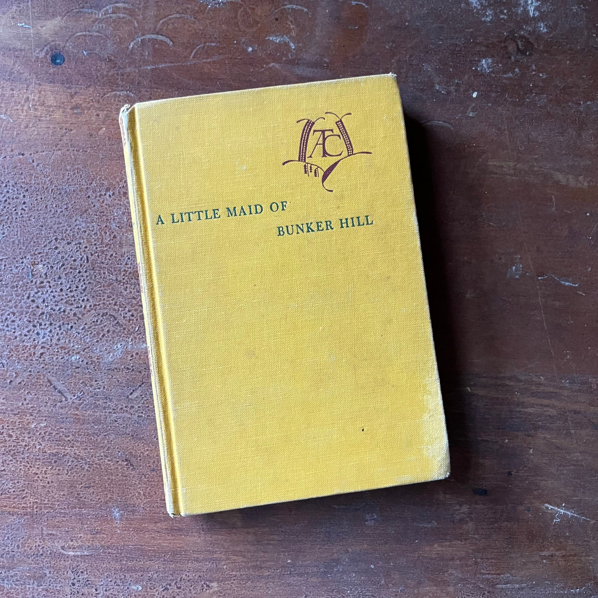 vintage children's living history book, vintage children's chapter book - A Little Maid of Bunker Hill written by Alice Turner Curtis with illustrations by Sandra James:  Published in 1952 by Alfred A. Knopf - view of the front cover in yellow with the title of the book in blue & the author's initials in a design in maroon