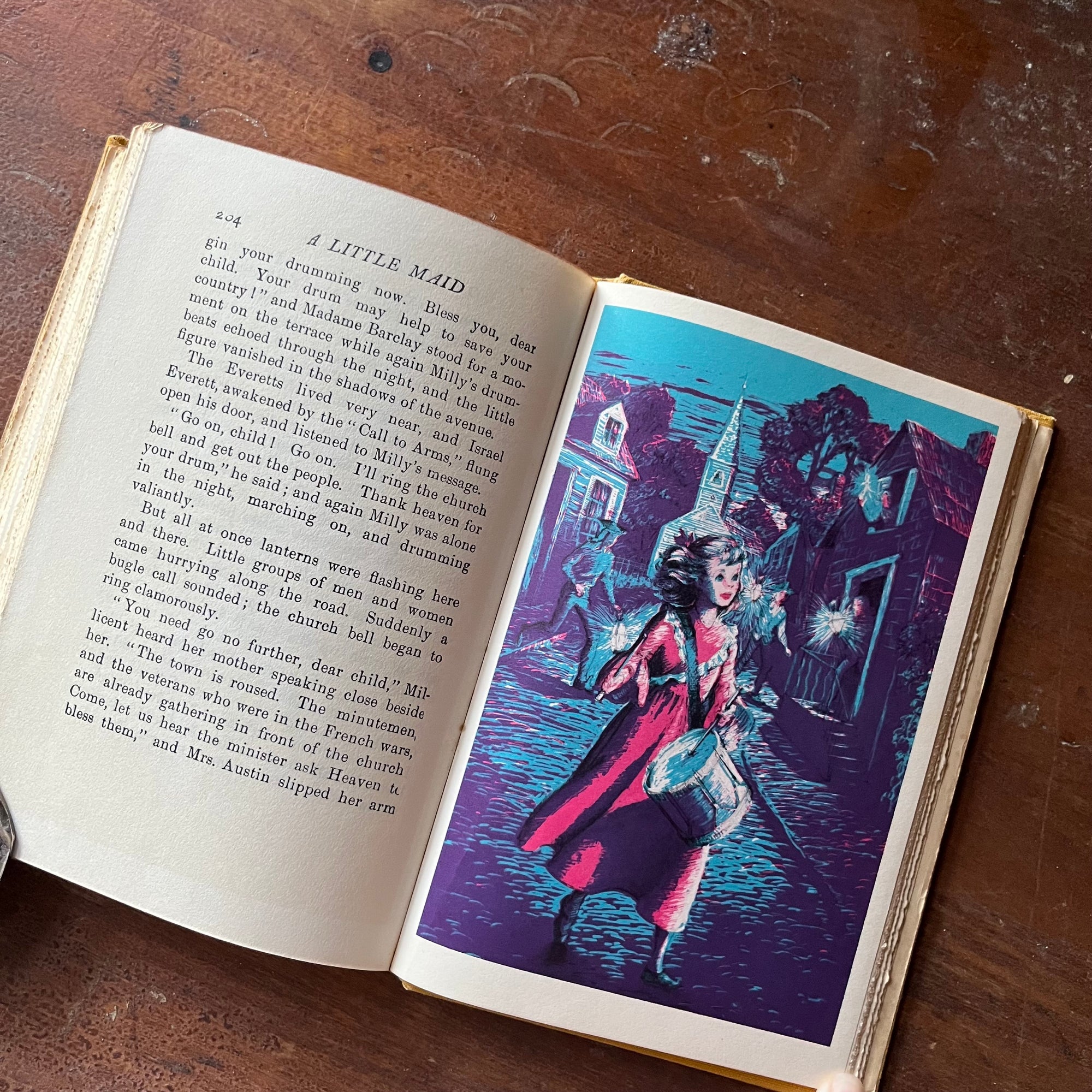 vintage children's living history book, vintage children's chapter book - A Little Maid of Bunker Hill written by Alice Turner Curtis with illustrations by Sandra James:  Published in 1952 by Alfred A. Knopf - view of the full color illustration of a little girl with a drum on a cobblestone street at night - she appears to be drumming to wake the citizens of the town in warning - there is a church in the background & several people coming out of their homes in response to her drumming