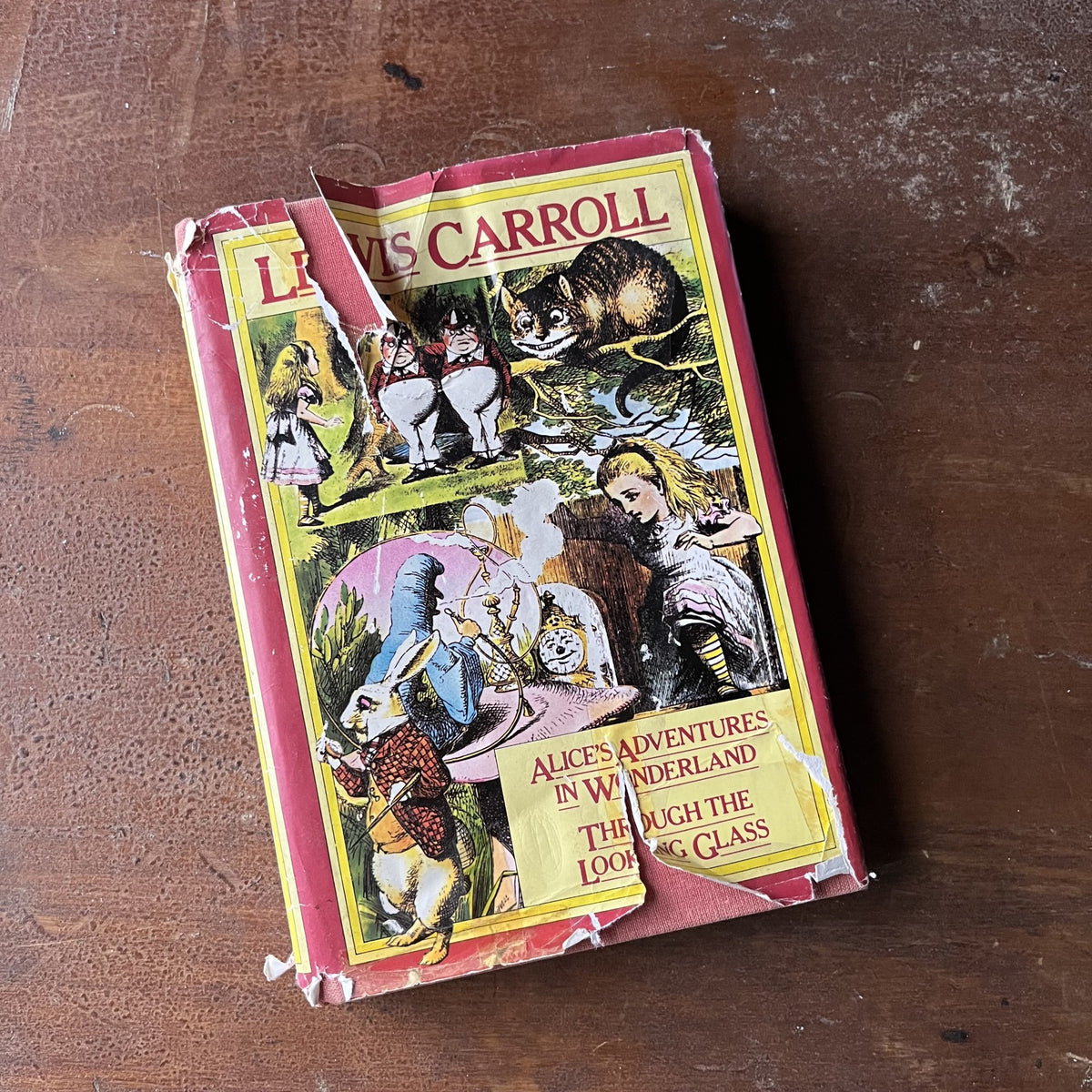 vintage children's chapter books - Alice's Adventures in Wonderland & Through the Looking Glass written by Lewis Carroll with illustrations by John Tenniel - view of the dust jacket's front cover with tears around the edges