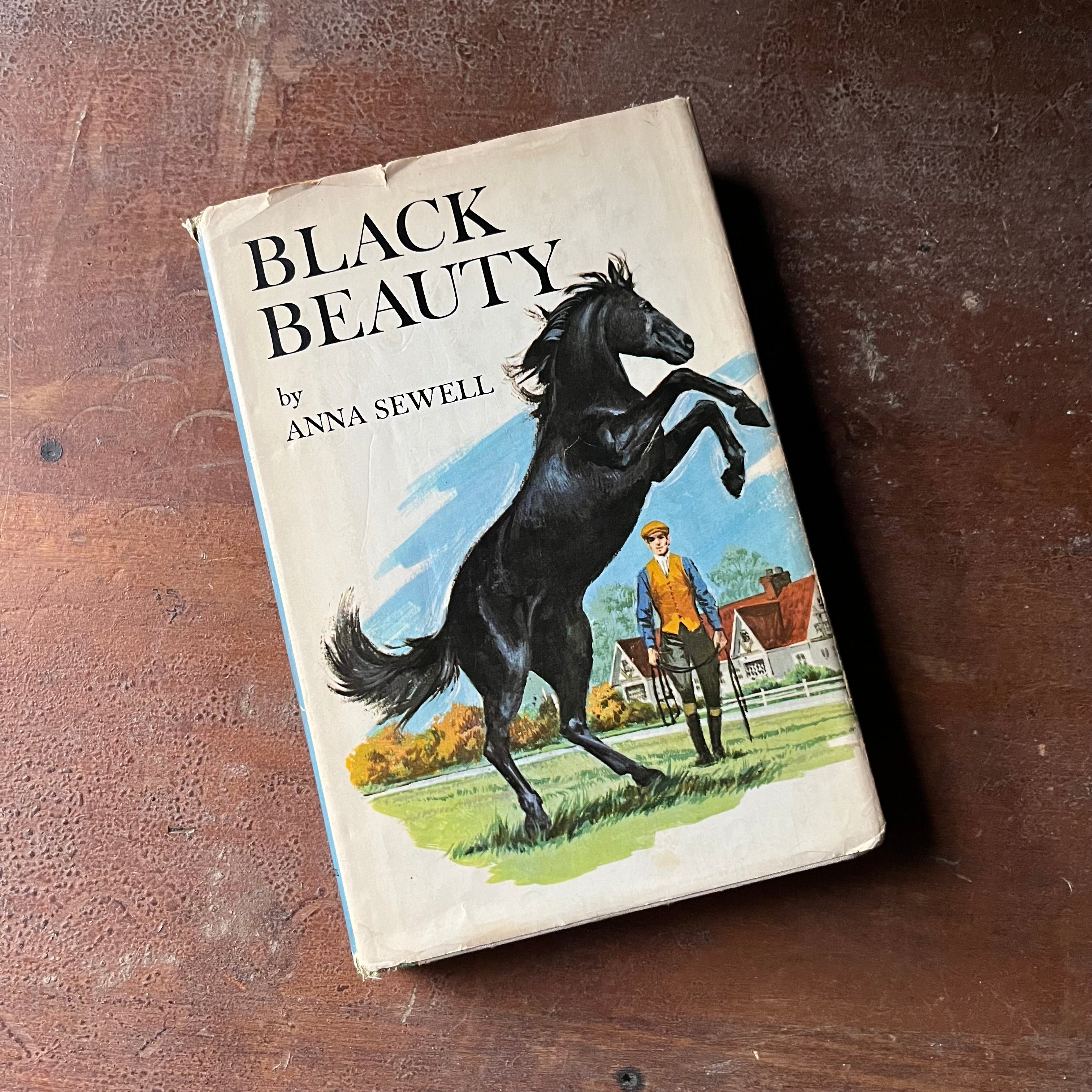 vintage children's chapter book, classic literature, horse story, Junior Deluxe Editions - Black Beauty written by Anna Sewell with illustrations by Walter Seaton - view of the dust jacket's front cover with an illustration of Black Beauty rearing on hind legs