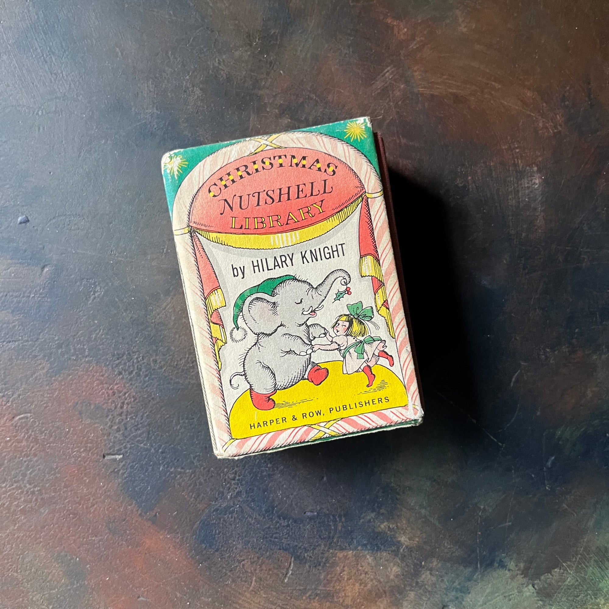 Christmas Nutshell Library By Hilary Knight-1963 Harper & Row, Publishers Edition-vintage Christmas Books-tiny books-view of the side of the book sleeve with an illustration of an elephant holding mistletoe