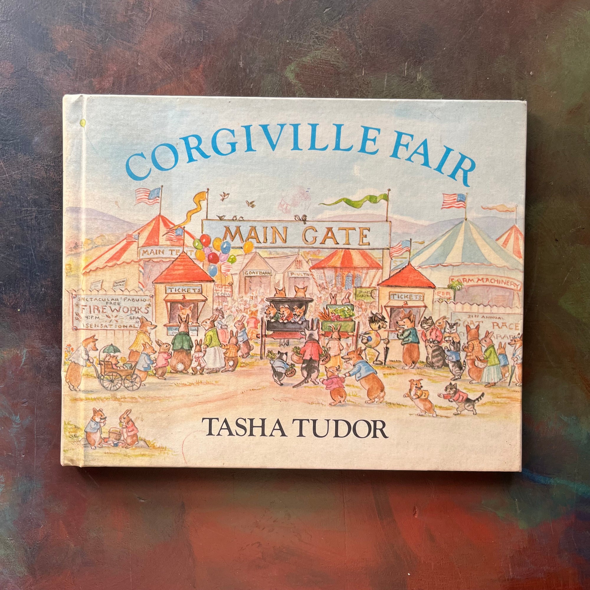 Corgiville Fair written and illustrated by Tasha Tudor-1971 First Edition-classic children's picture book-collector's edition-Corgi Dog Breed-view of the front cover sitting on a painted tabletop