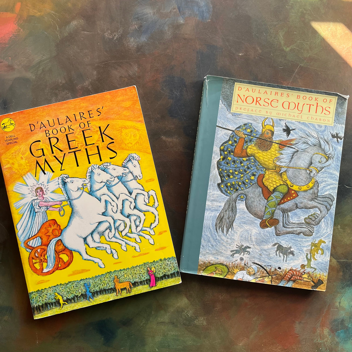 D'Aulaires' Book of Greek Myths and D'Aulaires' Book of Norse Myths written and illustrated by Ingri and Edgar Parin D'Aulaire - Homeschool Mythology Study Books- view of the dust jacket cover - greek god with chariot and horses on left hand cover and norse god on a horse on the right hand cover