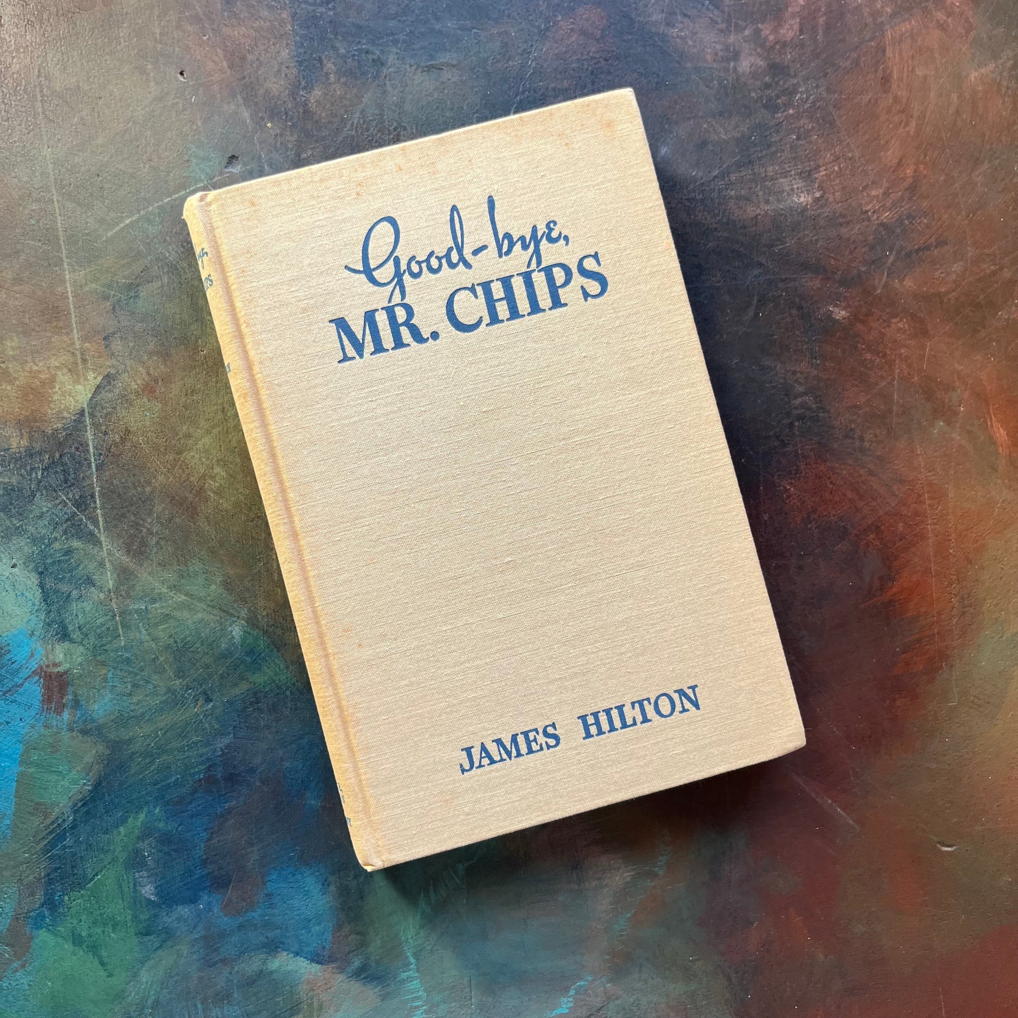 Good-Bye Mr. Chips written by James Hilton-Classic British Literature-vintage novella-heartwarming, wholesome story-view of the front cover of the book sitting on a painted table