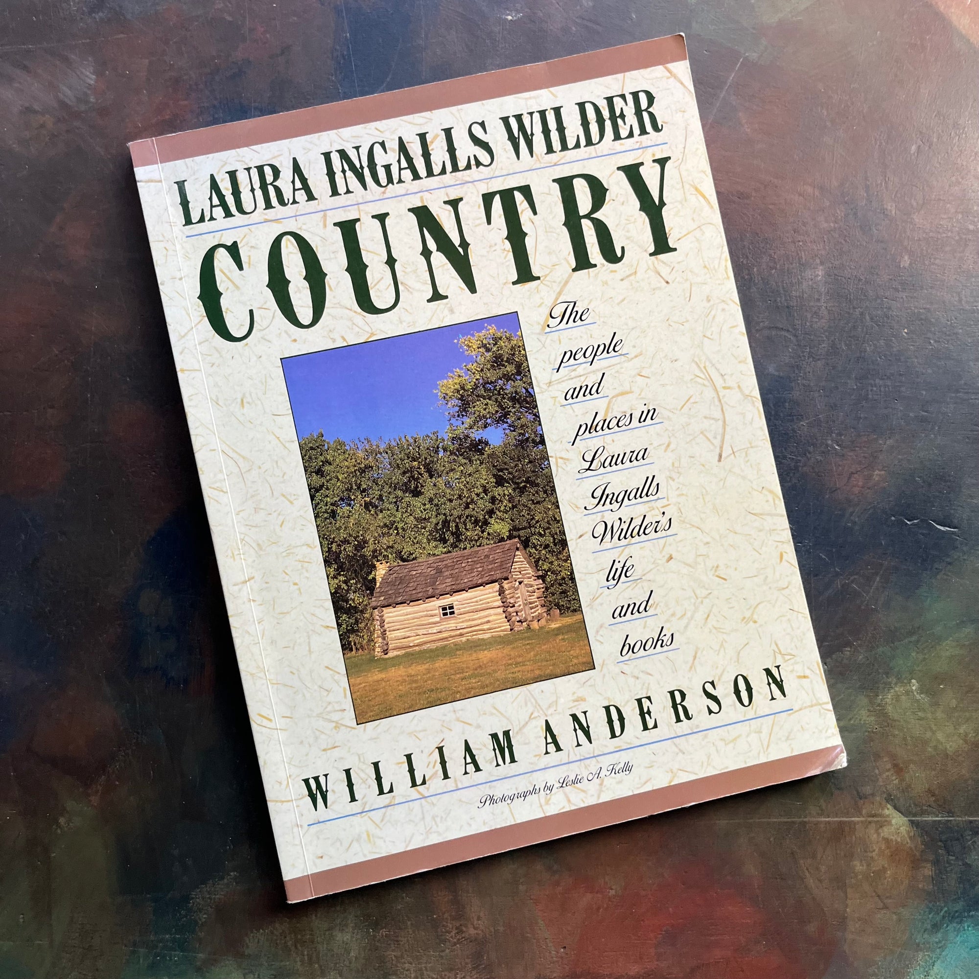 Laura Ingalls Wilder Country The People and Places in Laura Ingalls Wilder's Life and Books written by William Anderson-biography-view of the front cover with a photograph of a log cabin on the front surrounded by the title and author's name under it