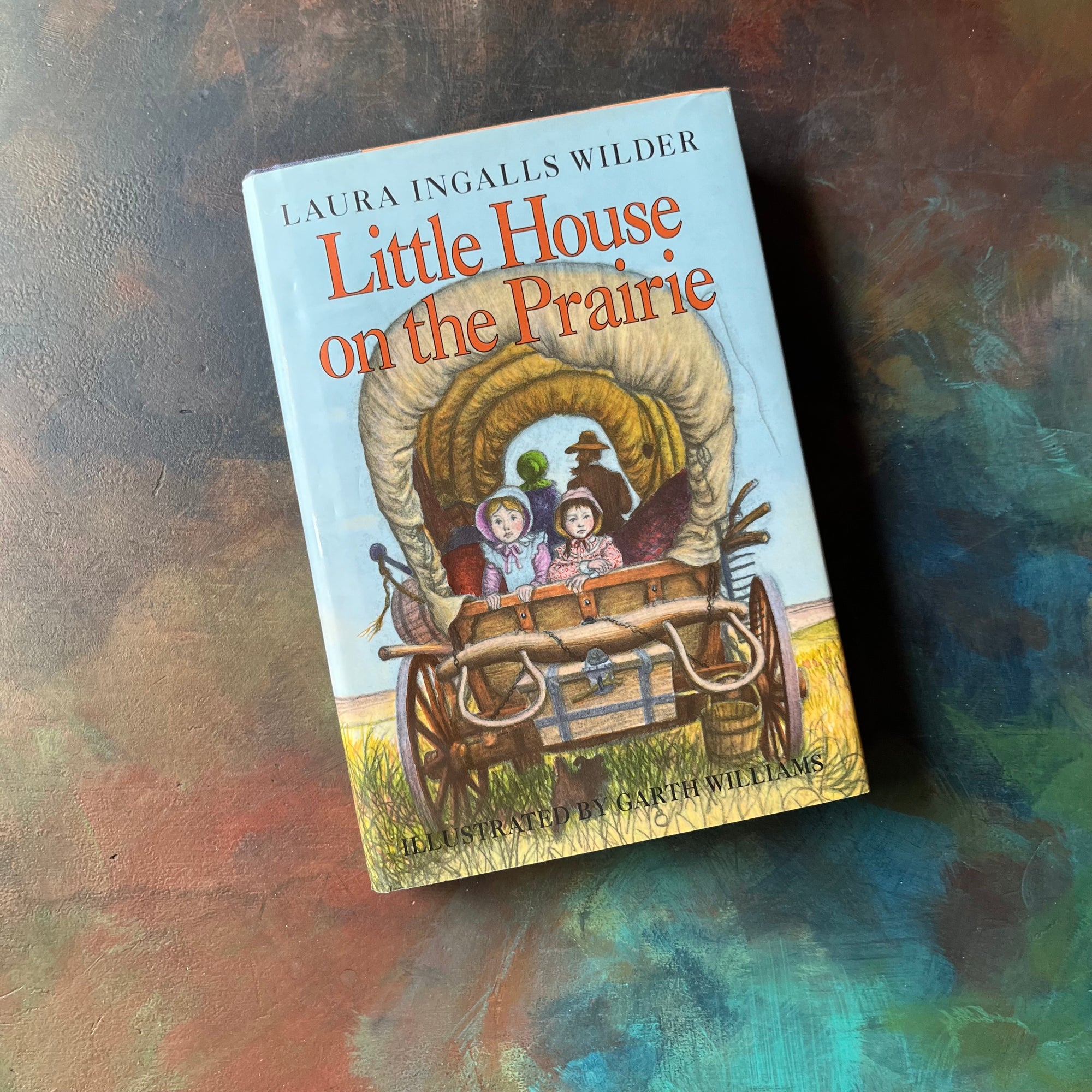 Little House on the Prairie by Laura Ingalls Wilder-Garth Williams-1991 Hardcover Edition-vintage living history book-children's fiction-view of the dust jacket's front cover with a picture of Laura & Mary in the back of the wagon with Jack under it & Ma & Pa in the background