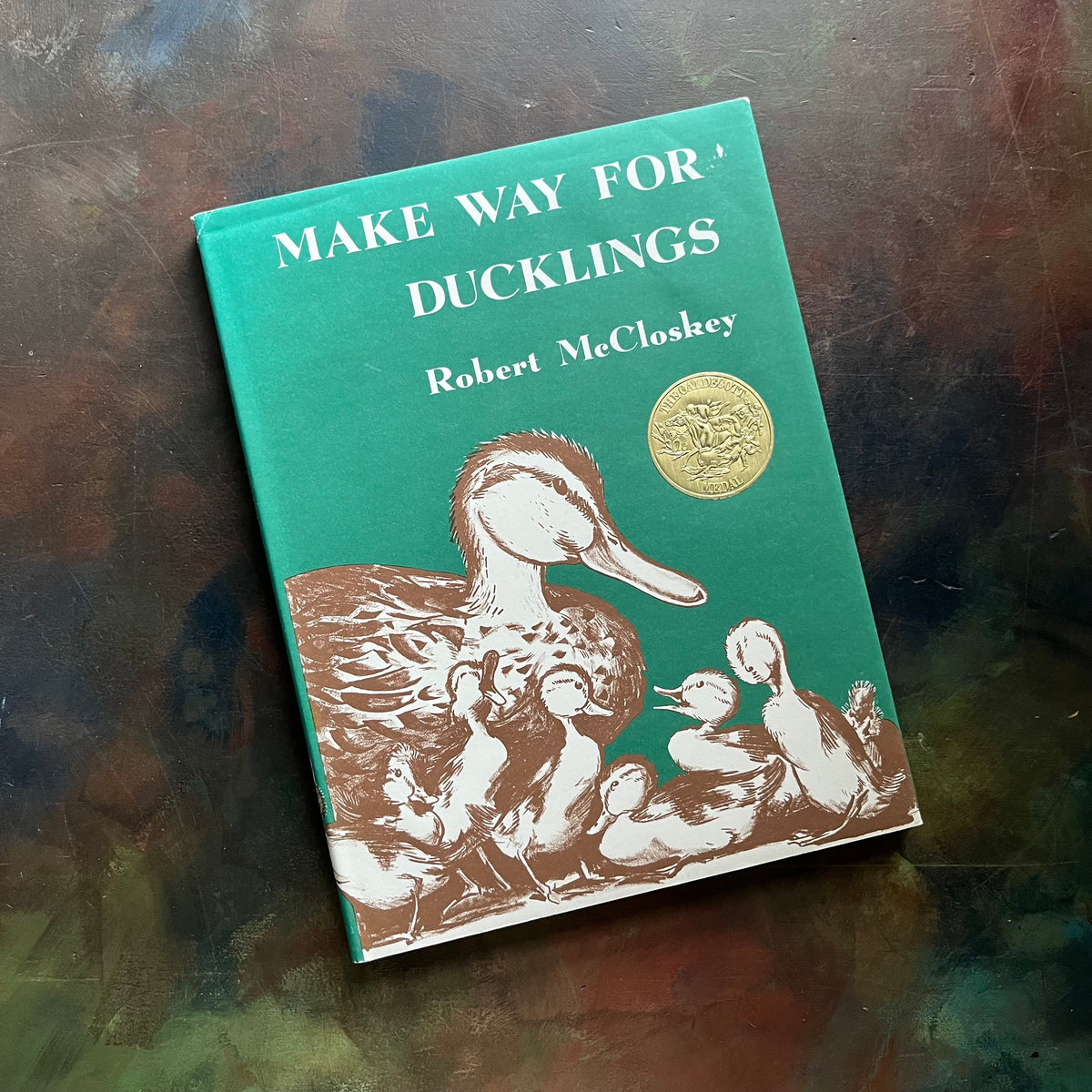 Make Way for Ducklings-Robert McCloskey-Caldecott Winning Picture Book-vintage children's picture book-must read children's book-Log Cabin Vintage Top 100 Must Read Children's Book-view of the dust jacket's front cover with Mrs. Mallard and her ducklings pictured along with a gold-colored Caldecott Medal Sticker shown