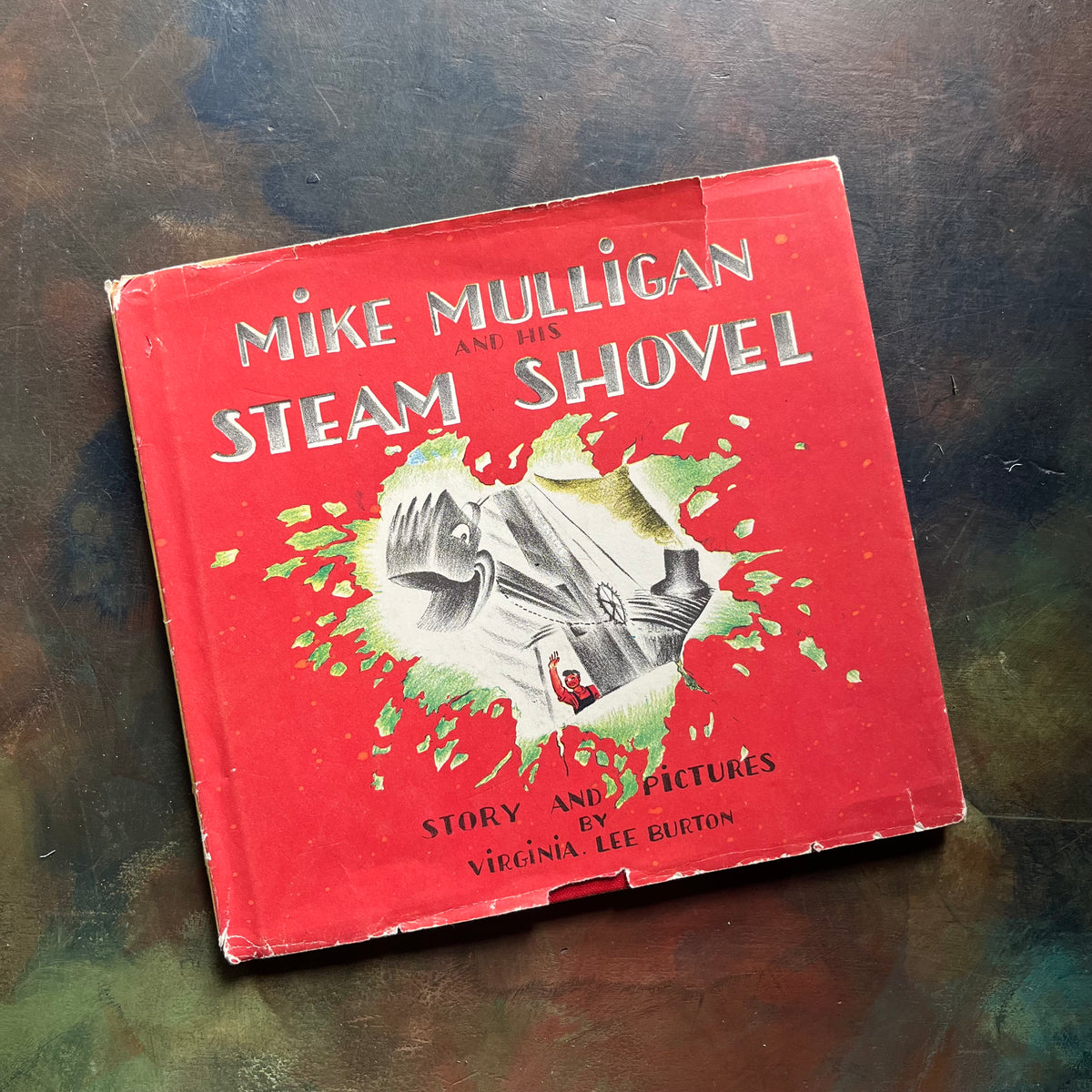 Mike Mulligan and His Steam Shovel written and illustrated by Virginia Lee Burton-rare 1939 First Edition Early Printing--vintage children's picture book-view of the dust jacket's front cover sitting on a textured tabletop