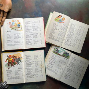 New Basic Readers published by Scott, Foresman and Company Publishers as part of the Curriculum Foundation Series. Four vintage children's schoolbooks spread out on a dark, textured tabletop, showing illustrated covers and open pages with chapter titles and character lists. The pages show copyright and content information for these books. 