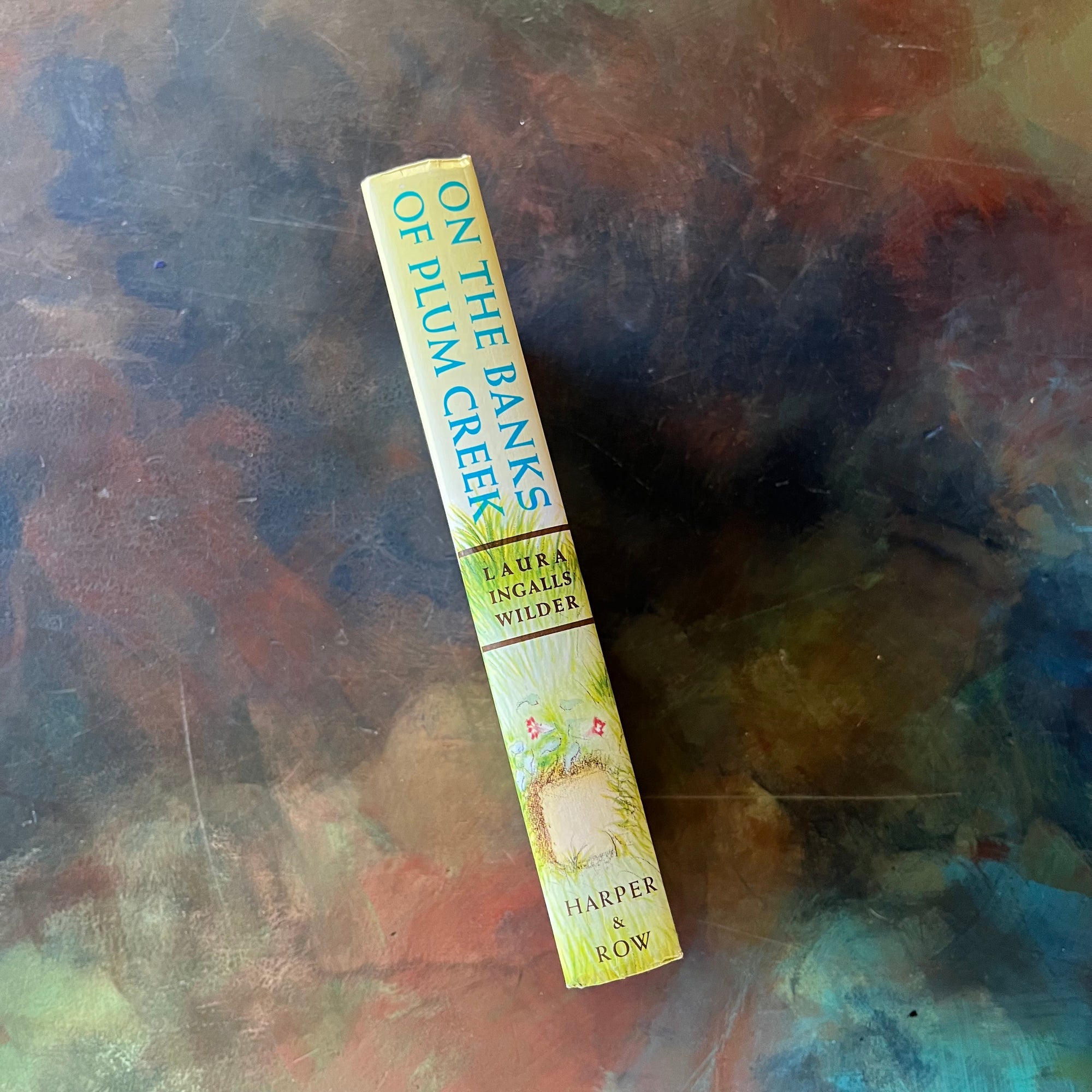 On the Banks of Plum Creek written by Laura Ingalls Wilder with illustrations by Garth Williams. This is a 1953 Edition by Harper & Row Publishers, New York & Evanston.  It was a 1938 Newbery Honor Book. 
 It is a vintage children's chapter book & living book.  View of the spine.