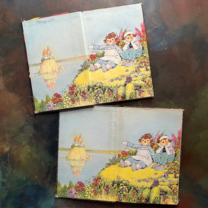 Pair of Raggedy Ann Books and Andy Books written by Johnny Gruelle-Raggedy Ann's Lucky Pennies-Beloved Belindy-classic children's books-view of the inside covers with the same image of Raggedy Ann and Andy on what appears to be a shore with Raggedy Ann pointing to an island with a castle on it