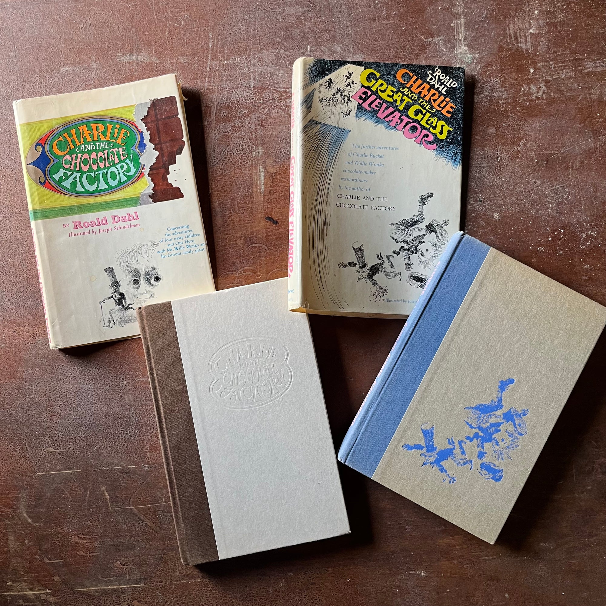 vintage children's chapter books - Pair of Roald Dahl Books-Charlie & The Chocolate Factory and Charlie & The Great Glass Elevator with illustrations by Joseph Schindelman - view of the embossed front covers - one with the title embossed & one with a blue illustration