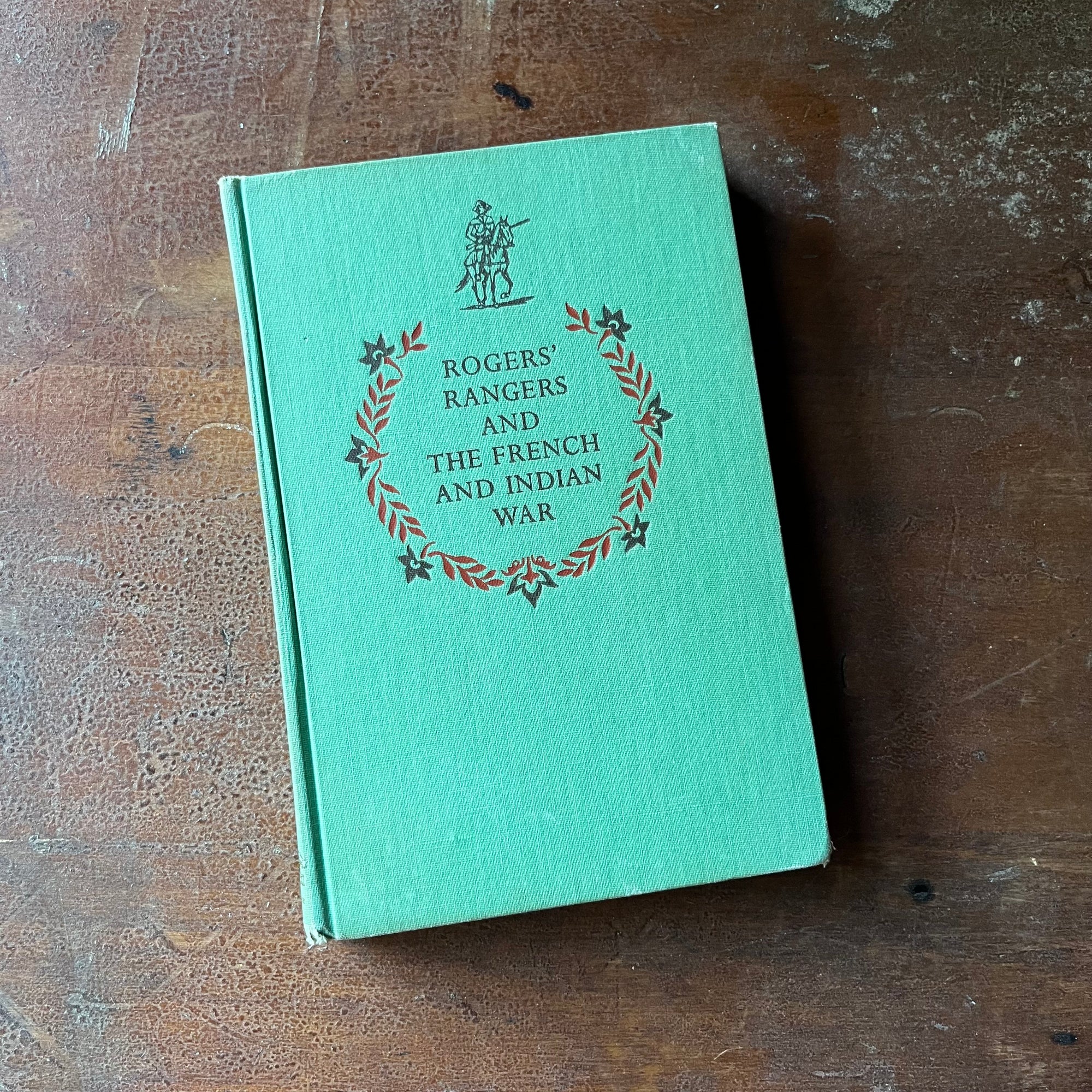 vintage children's living history book - Rogers' Rangers and The French and Indian War written by Bradford Smith with illustrations by John C. Wonsetler - view of the embossed front cover - green with a soldier on horseback along with the title embossed under the illustration - the wreath surrounds the title - the wreath is found on all early Landmark Series books