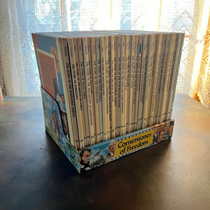 Set of 34 Cornerstones of Freedom History Books for Children in cardboard sleeve holder-vintage US History Picture Books-Early Readers-America250-view of the spines sitting inside the cardboard sleeve holder.