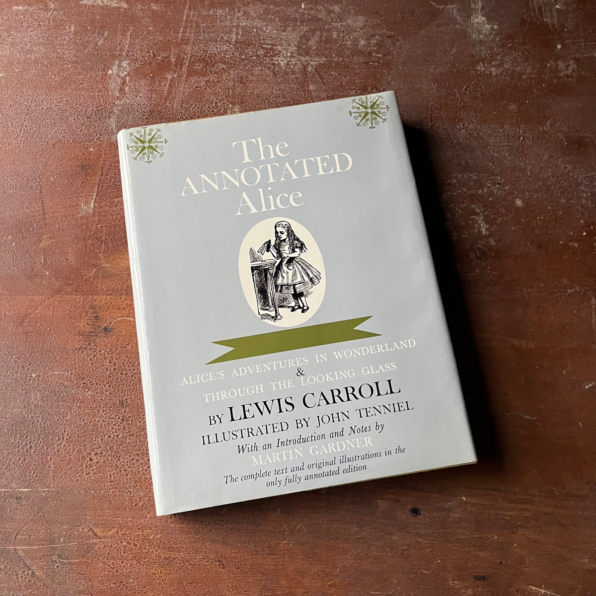 The Annotated Alice-Alice's Adventure's in Wonderland & Through the Looking Glass by Lewis Carroll-Notes by Martin Gardner--view of the dust jacket's front cover in a light blue with an illustration of Alice in the middle