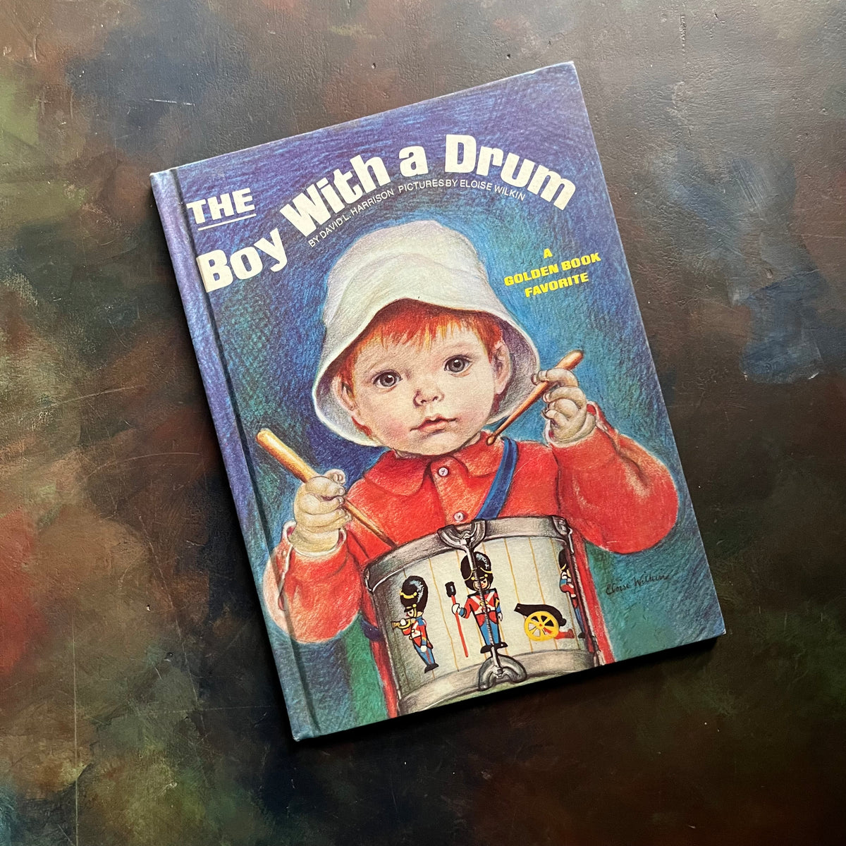 Book titled 'The Boy With a Drum' on a textured surface-The Boy With a Drum by David L. Harrison-Illustrated by Eloise Wilkin-A Golden Book Favorite-oversized Golden Book-view of the front cover.
