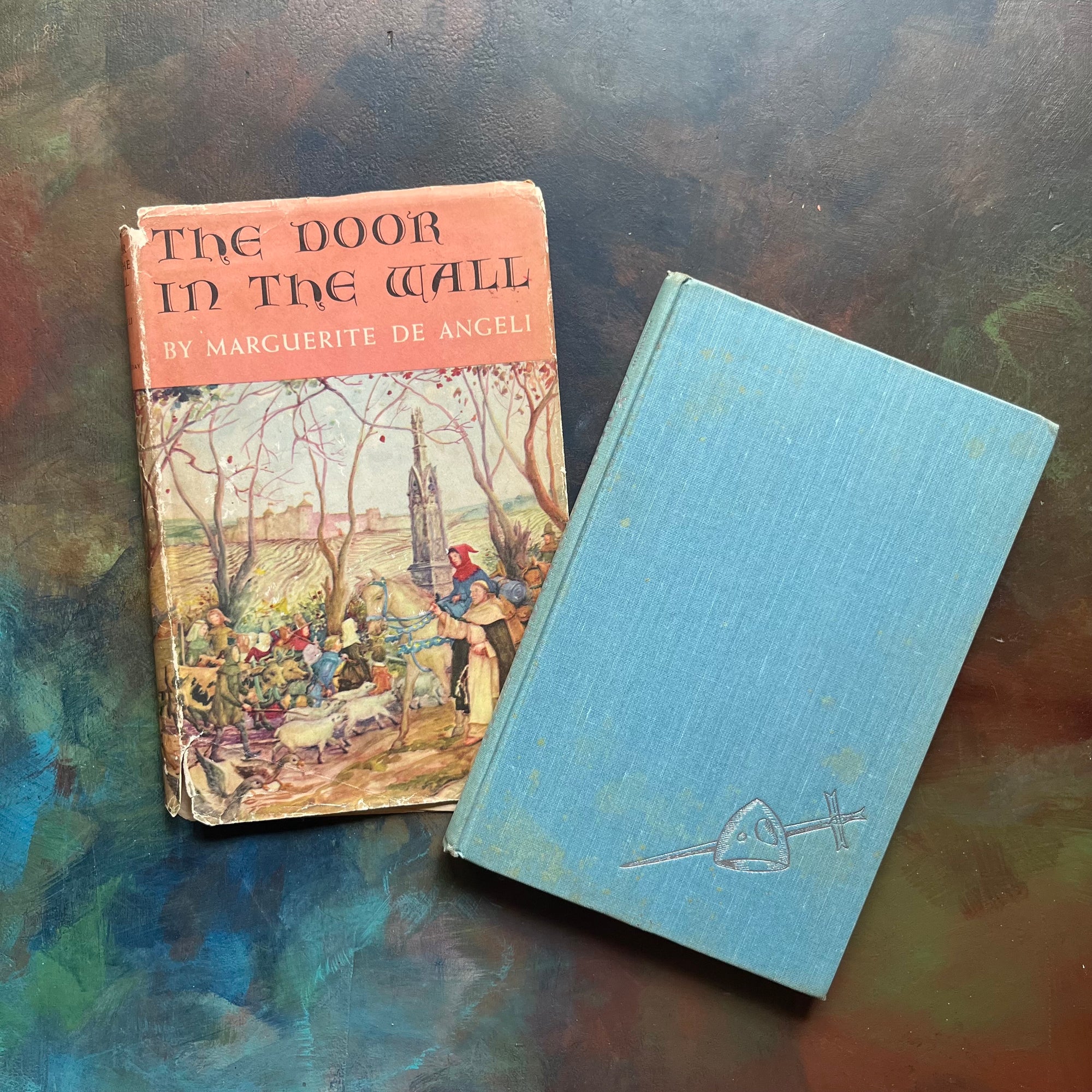 The Door in the Wall Written by Marguerite de Angeli-1950 Newbery Award Winning Book-vintage children's chapter book-view of the embossed front cover in blue with a sword & shield in silver