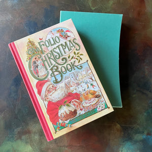 The Folio Christmas Book by The Folio Society of London-A Collection of Seasonal Stories and Poems-classic Christmas Stories & Poems-view of the front cover with different Christmas/holiday images in the cover design including Santa, a couple sledding, people kissing under mistletoe, etc.