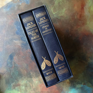 The Jack London Library 2 Volume Set-Tales of the North-Stories of Adventure-Books in Sleeve-Classic American Literature-Gift Book Set-view of the spines of both books tucked into the book sleeve - snowshoes are on the spines along with the title, publisher & a design - all in gilt