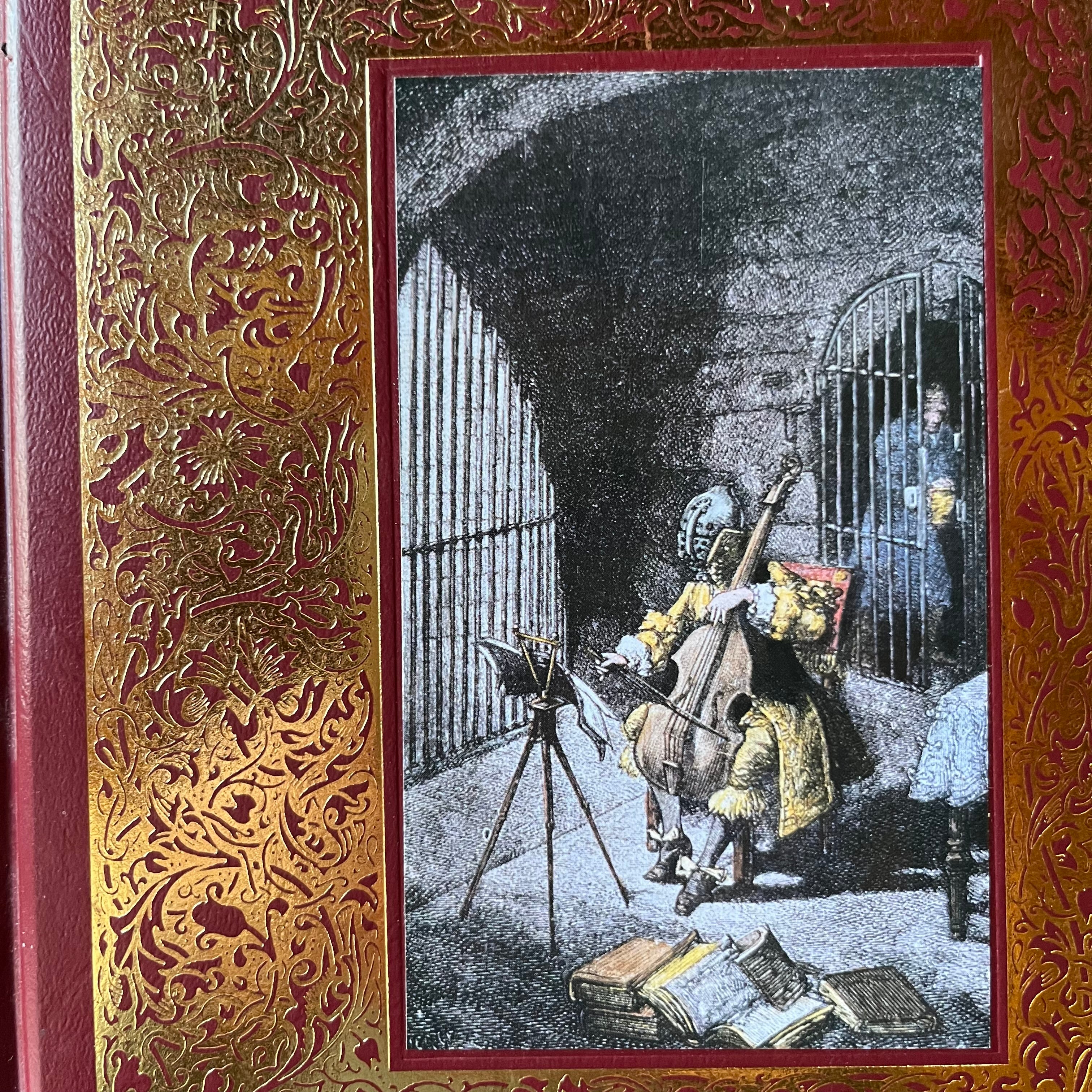The Man in the Iron Mask by Alexandre Dumas-Trident Press International Leatherbound Collectible Edition-classic literature-gift book-view of a closeup of the cover design depicting the main character in a mask playing a cello in a prison cell