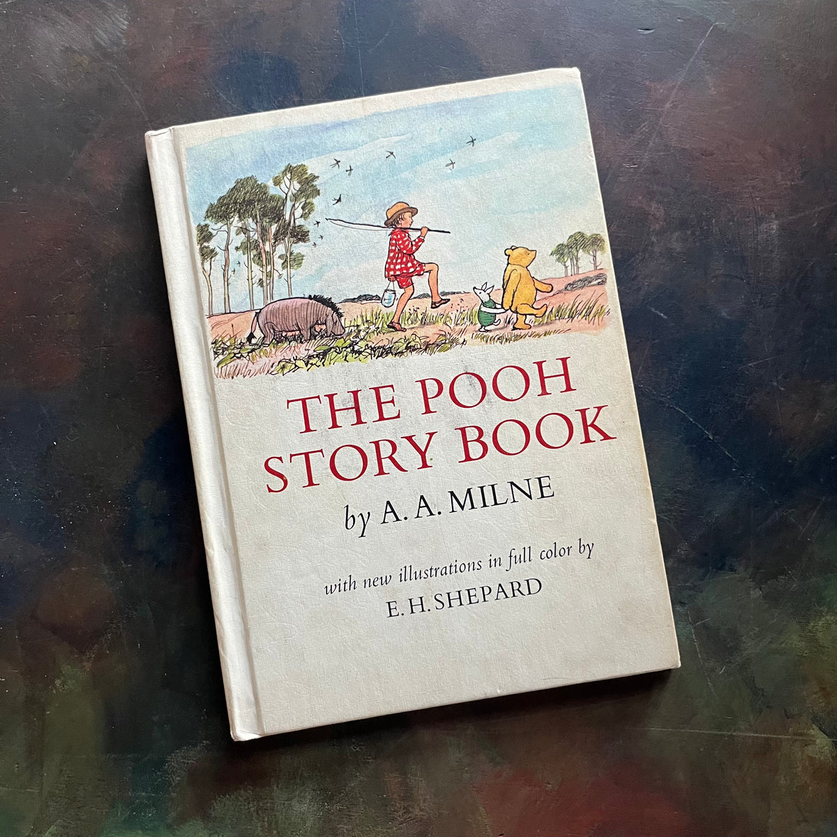 The Pooh Story Book written by A.A. Milne with black and white and color illustrations by E.H. Shepard-classic picture book-read aloud favorite-a log cabin 100 book-view of the front cover with winnie, eyore, Christoper Robin and piglet on the cover walking in a line