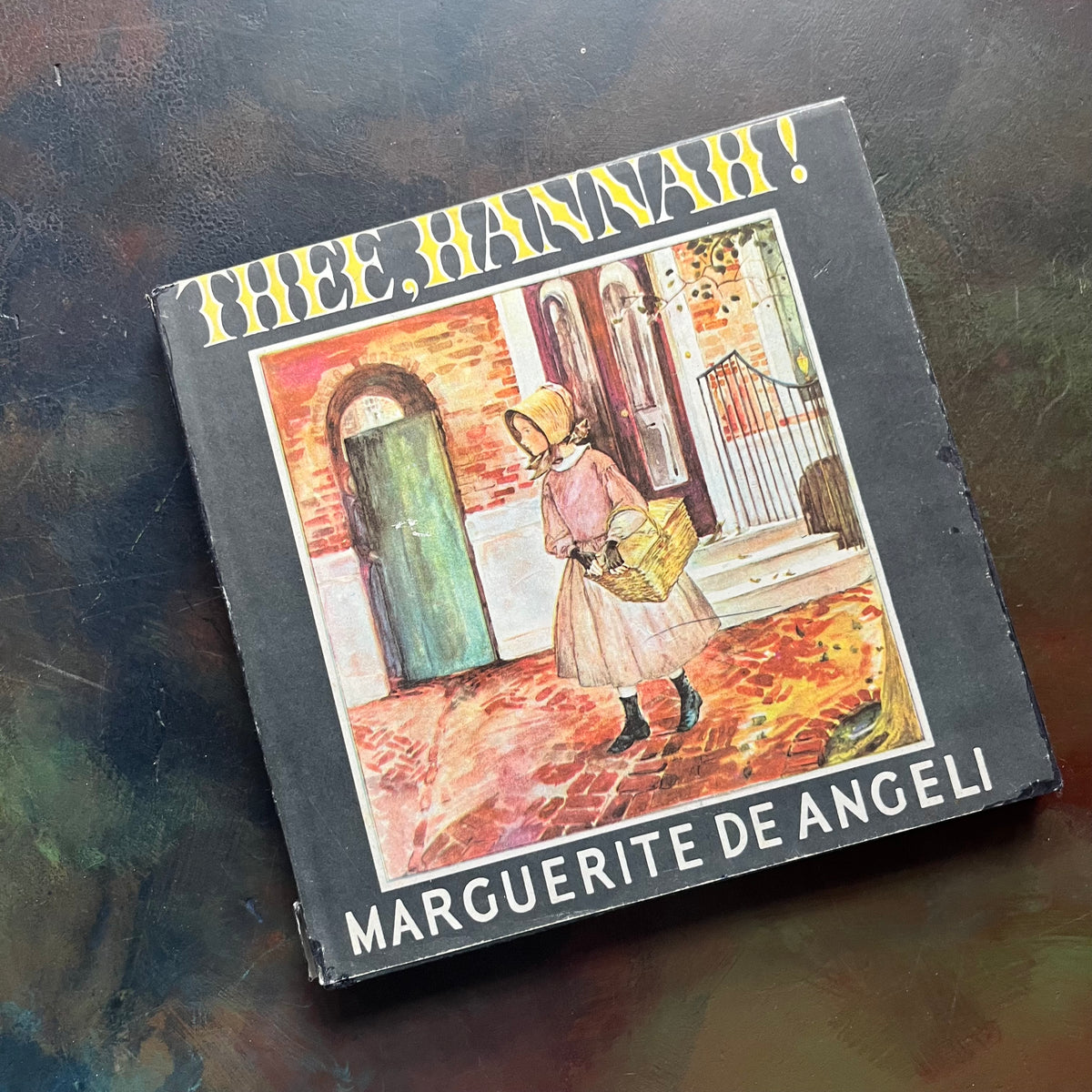 Thee, Hannah! written and illustrated by Marguerite de Angeli-antique children's book-PA Quaker history-vintage children's picture book-view of the front cover of the dust jacket depicting Hannah with a shopping basket walking a cobble-stoned Philadelphia street.