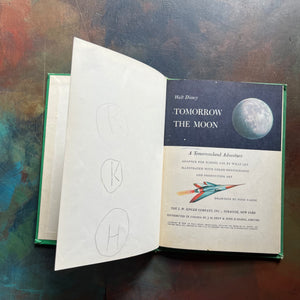Vintage Green book titled 'Tomorrow the Moon' by Walt Disney on a textured surface-A Tomorrowland Adventure Book-Walt Disney Productions-living science book for kids-view of the title page - note the pencil drawings on the page opposite the title page