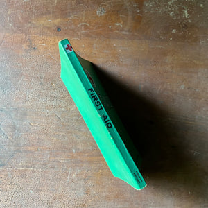 The American Red Cross First Aid Textbook 4th Edition - spine shown sitting on a wood table