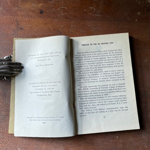 The American Red Cross First Aid Textbook 4th Edition - book opened to the copyright page & shown sitting on a wood table