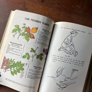 The American Red Cross First Aid Textbook 4th Edition - book opened to show both color & black & white illustrations - shown sitting on a wood table