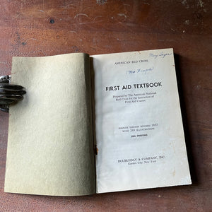 The American Red Cross First Aid Textbook 4th Edition - book opened to title page shown sitting on a wood table