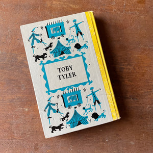 Log Cabin Vintage - vintage children's book, children's book, chapter book, Junior Deluxe Editions Book - Toby Tyler by James Otis with illustrations by Leonard Weisgard - 1958 Edition - view of the embossed back cover sitting on a wood table