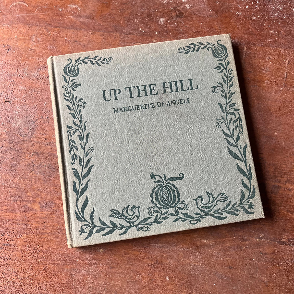 Log Cabin Vintage – vintage children’s book, children’s book, chapter book - Up the hill by Marguerite de Angeli 1942 Edition - view of the book sitting on a wood tabletop with the front cover showing